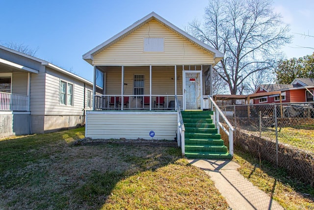 view of front of home with covered porch, fence, and a front lawn