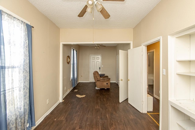 corridor with a textured ceiling, baseboards, and wood finished floors