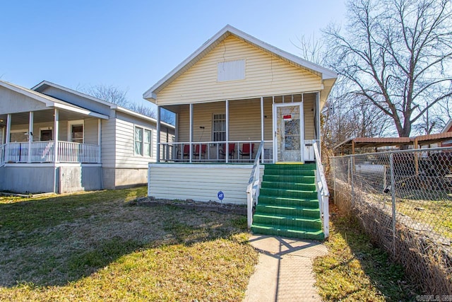 view of front facade featuring a porch, a front yard, and fence