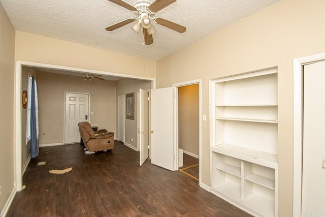 interior space featuring ceiling fan, a textured ceiling, baseboards, and wood finished floors