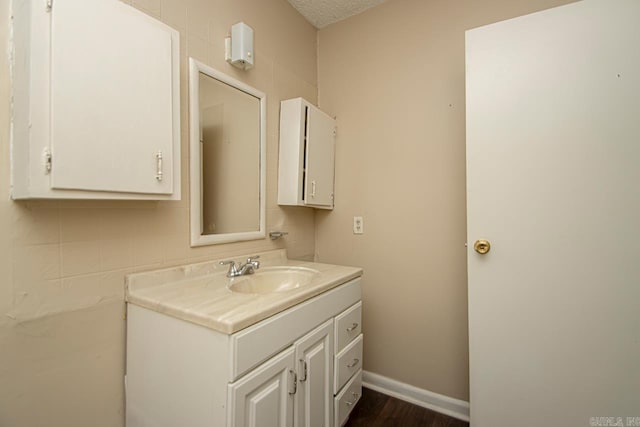 bathroom featuring baseboards, wood finished floors, a textured ceiling, and vanity