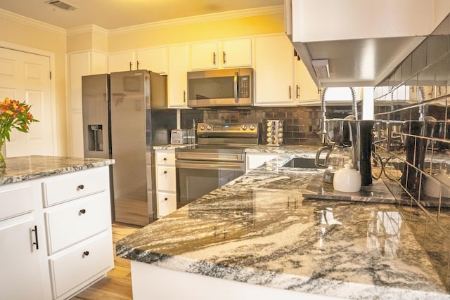 kitchen featuring light stone countertops, light wood-style floors, appliances with stainless steel finishes, decorative backsplash, and crown molding