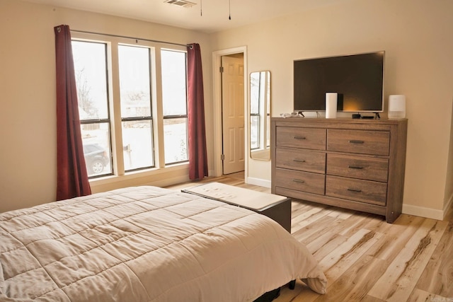 bedroom featuring light wood finished floors, baseboards, and visible vents