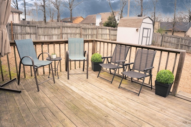 wooden terrace with an outbuilding, a fenced backyard, and a shed