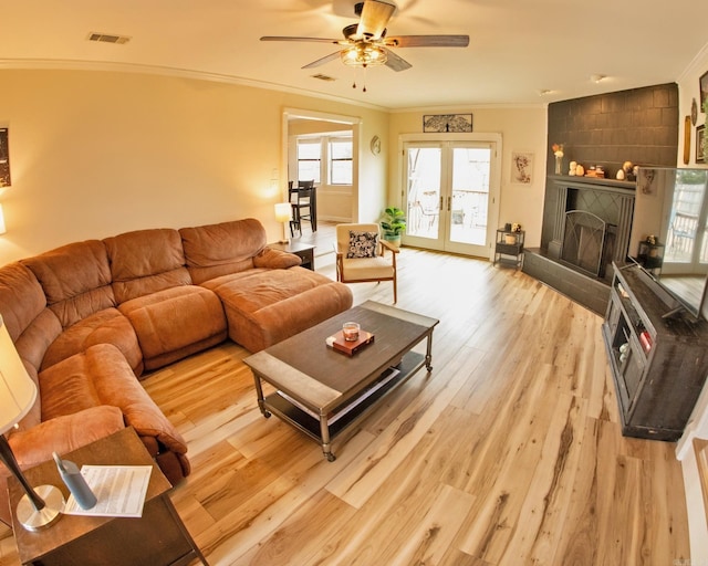 living area featuring light wood-style floors, visible vents, crown molding, and french doors