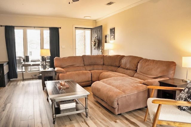 living room with light wood-style floors, visible vents, and crown molding