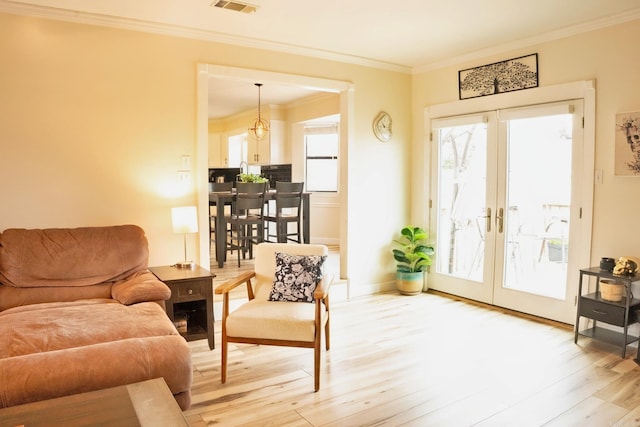 living area with visible vents, baseboards, ornamental molding, french doors, and light wood-type flooring