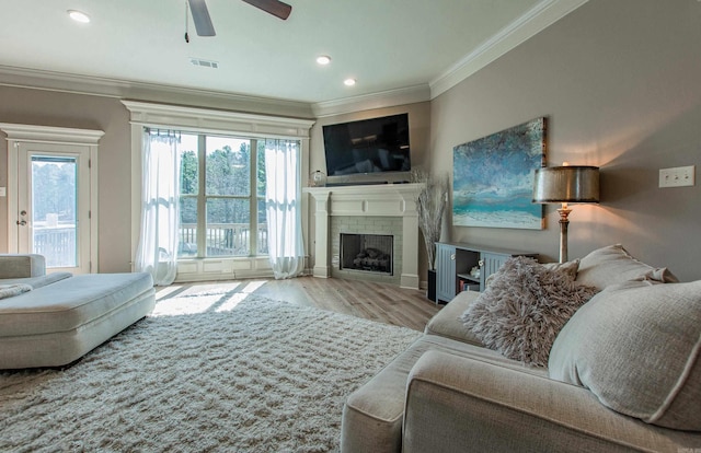 living area with visible vents, wood finished floors, a wealth of natural light, and crown molding