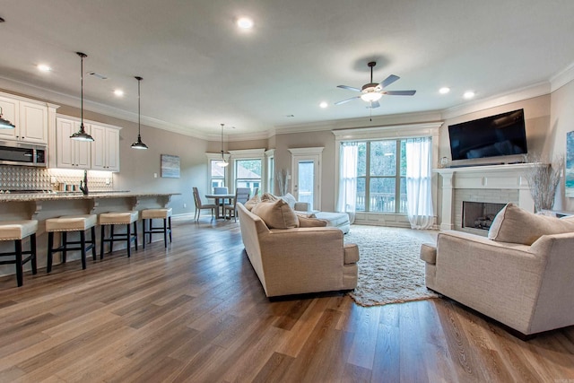 living area with plenty of natural light, a brick fireplace, wood finished floors, and baseboards