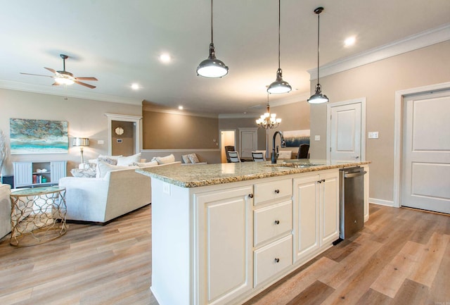 kitchen featuring a sink, white cabinets, open floor plan, light wood-type flooring, and a center island with sink