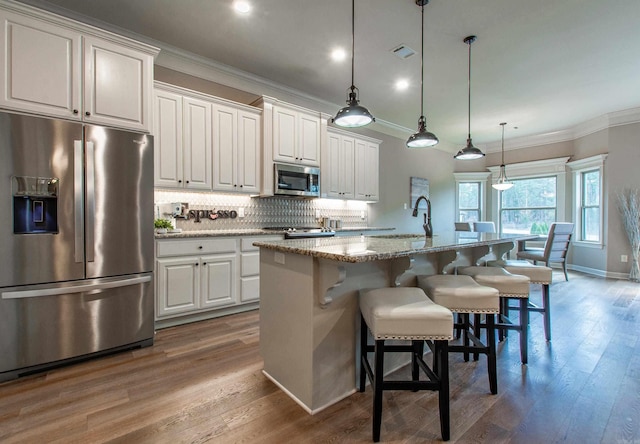 kitchen featuring tasteful backsplash, appliances with stainless steel finishes, crown molding, and wood finished floors