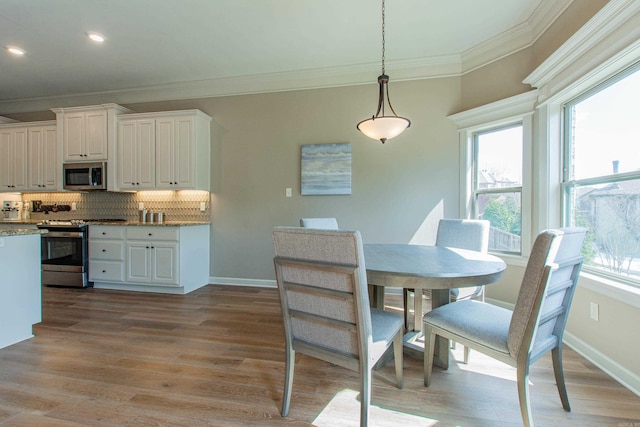 dining space with light wood finished floors, baseboards, crown molding, and recessed lighting