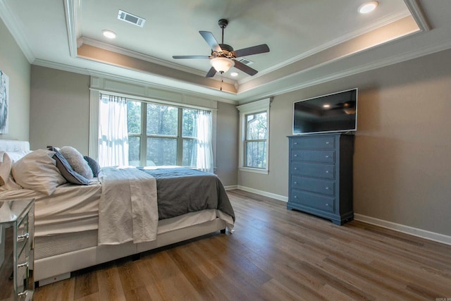bedroom with a raised ceiling, visible vents, and wood finished floors