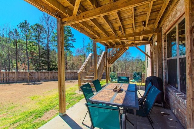 view of patio / terrace featuring stairs, outdoor dining space, and a fenced backyard