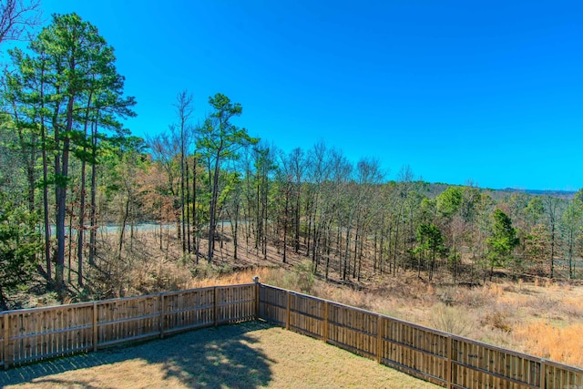 view of yard featuring a fenced backyard and a view of trees