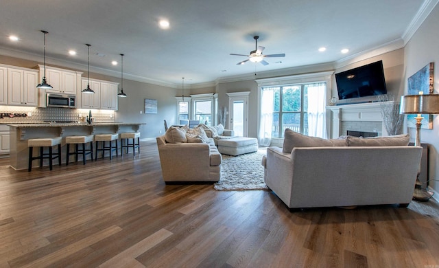 living room featuring a fireplace, dark wood finished floors, crown molding, and recessed lighting