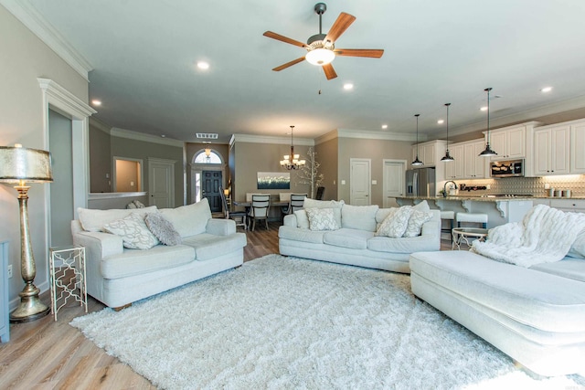 living area featuring light wood-type flooring, recessed lighting, visible vents, and ceiling fan with notable chandelier