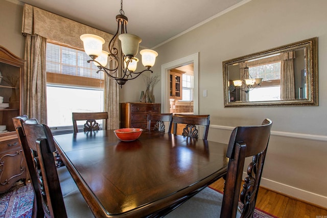 dining space featuring crown molding, a notable chandelier, baseboards, and wood finished floors