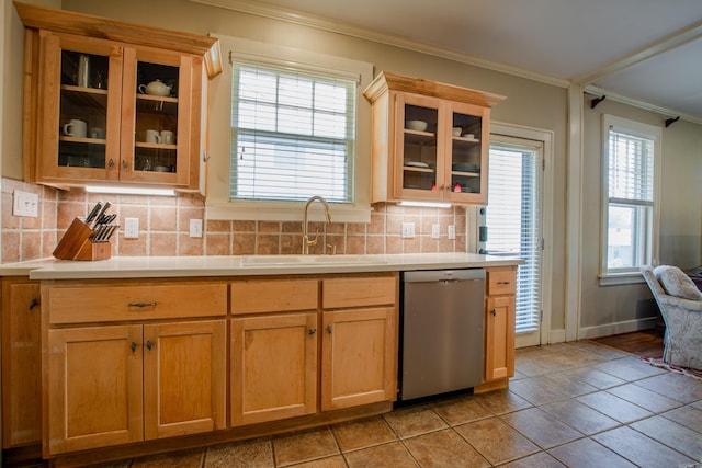 kitchen with backsplash, light countertops, crown molding, stainless steel dishwasher, and a sink