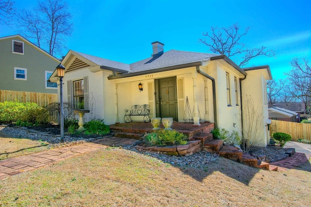 bungalow-style house with a shingled roof, a chimney, fence, and stucco siding