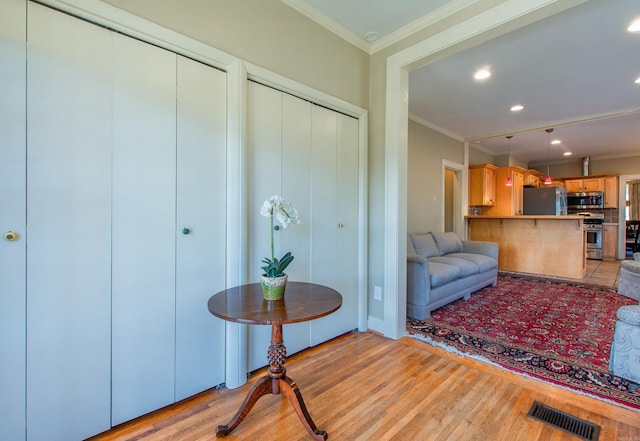 living room featuring light wood finished floors, visible vents, crown molding, and recessed lighting