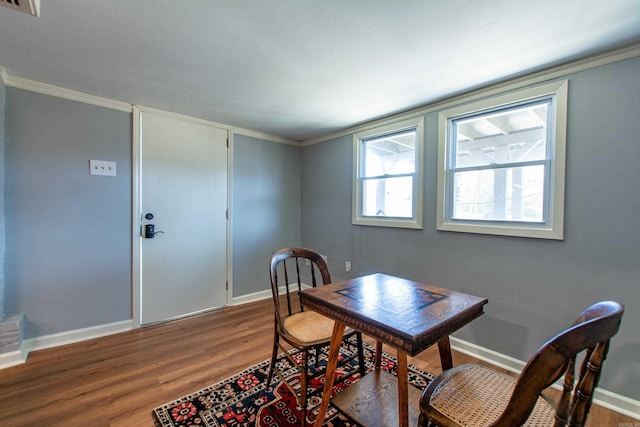 dining room with crown molding, baseboards, and wood finished floors