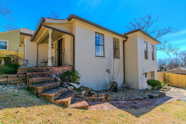 view of property exterior featuring fence and brick siding