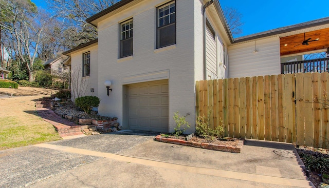 view of front of house featuring a garage, driveway, fence, and a ceiling fan