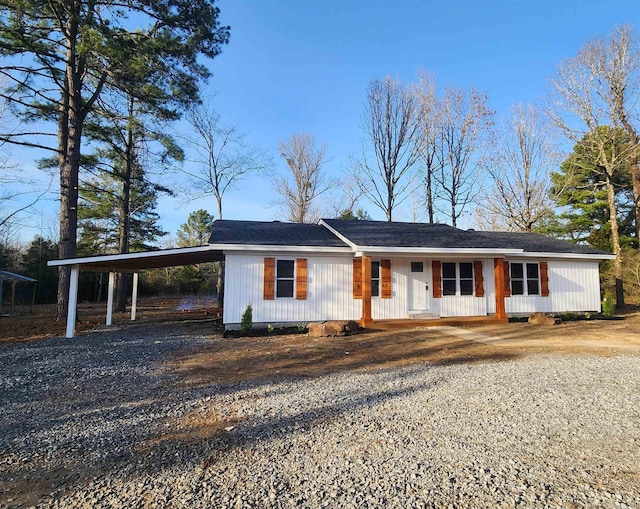 single story home with a carport, gravel driveway, and a porch