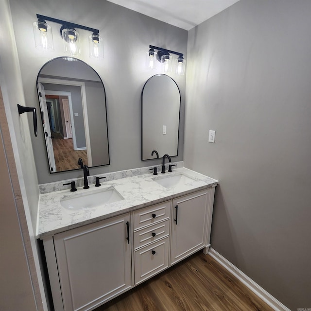 bathroom featuring double vanity, a sink, baseboards, and wood finished floors