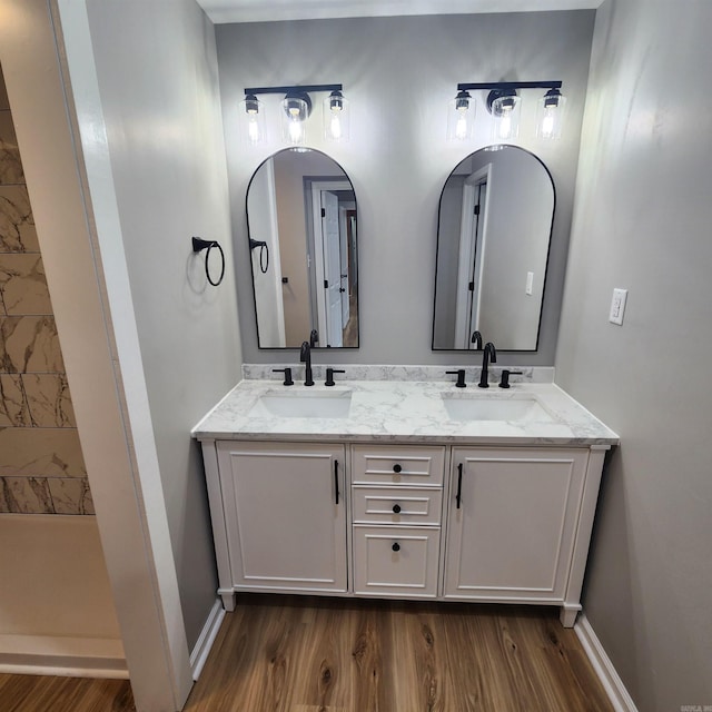 bathroom featuring double vanity, baseboards, a sink, and wood finished floors