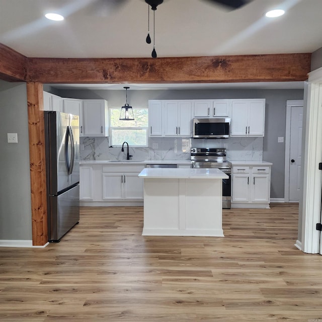 kitchen with light wood finished floors, white cabinets, stainless steel appliances, light countertops, and backsplash