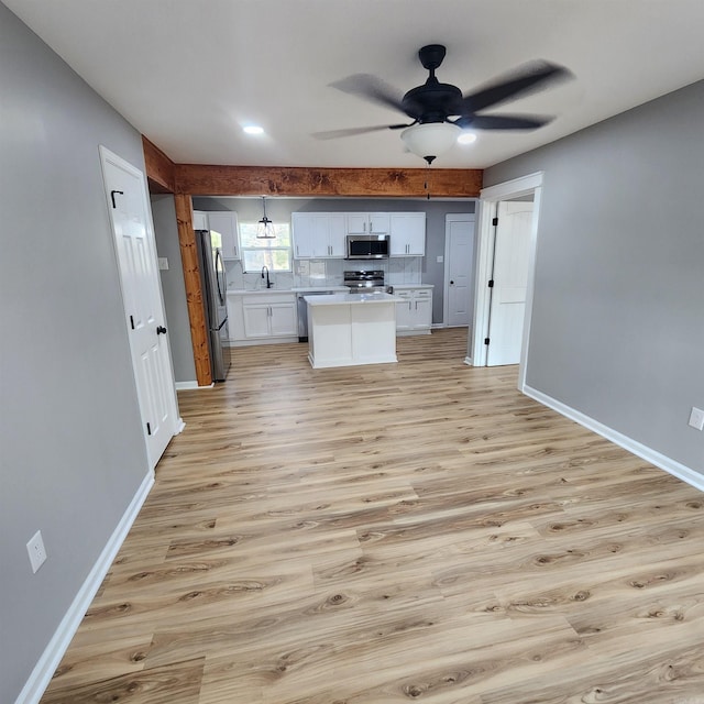 kitchen featuring appliances with stainless steel finishes, light countertops, light wood-style flooring, and white cabinetry