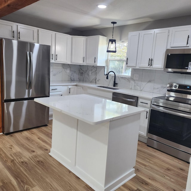 kitchen featuring a sink, white cabinetry, appliances with stainless steel finishes, decorative backsplash, and light wood finished floors