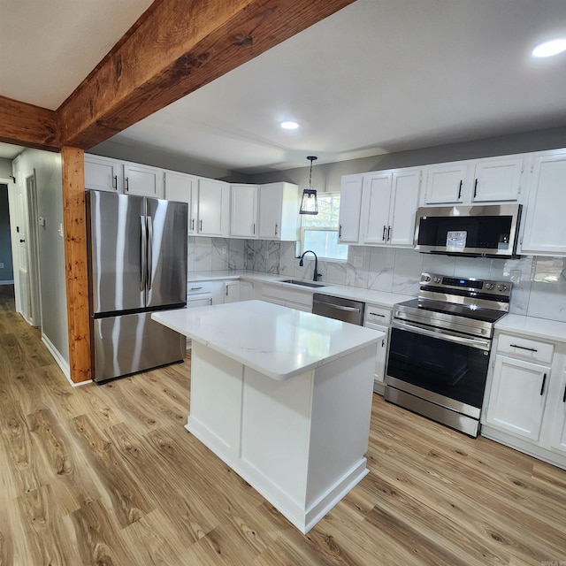 kitchen with light wood finished floors, stainless steel appliances, decorative backsplash, a sink, and beamed ceiling