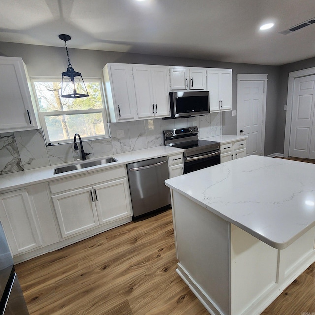 kitchen with visible vents, light wood-style flooring, stainless steel appliances, white cabinetry, and a sink