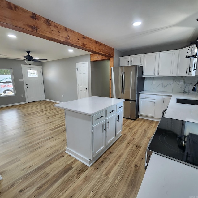 kitchen featuring light wood finished floors, light countertops, appliances with stainless steel finishes, and beam ceiling