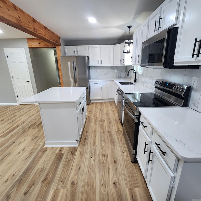 kitchen with light wood-style flooring, a sink, appliances with stainless steel finishes, backsplash, and a center island