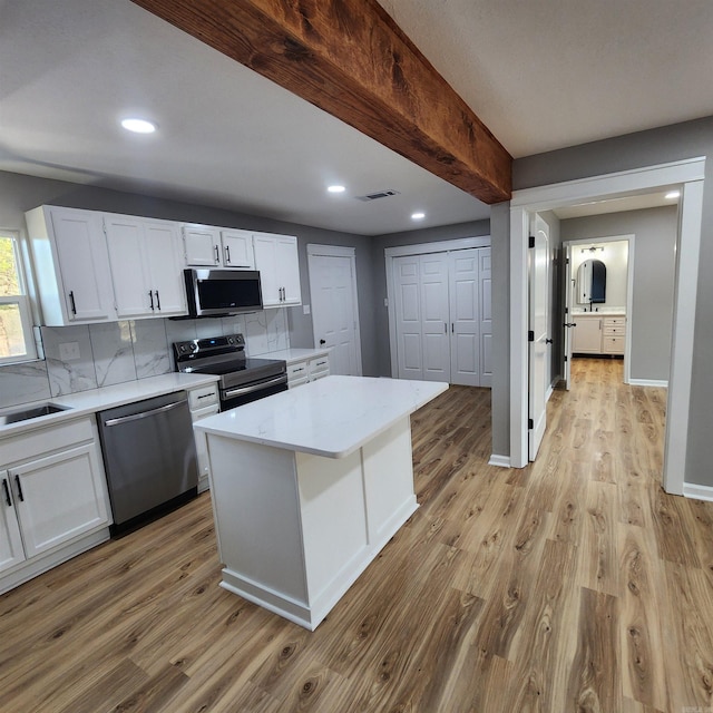 kitchen with visible vents, appliances with stainless steel finishes, light wood-style floors, white cabinetry, and backsplash