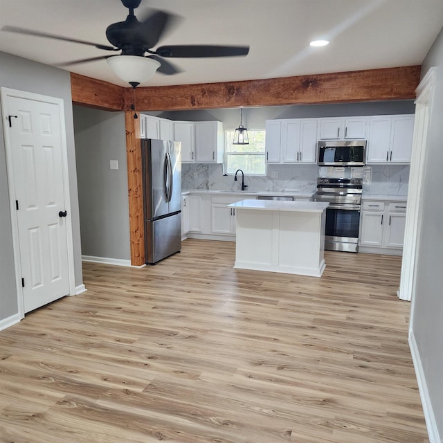 kitchen with tasteful backsplash, light countertops, appliances with stainless steel finishes, white cabinetry, and a sink