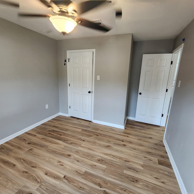 unfurnished room with light wood finished floors, baseboards, and a ceiling fan