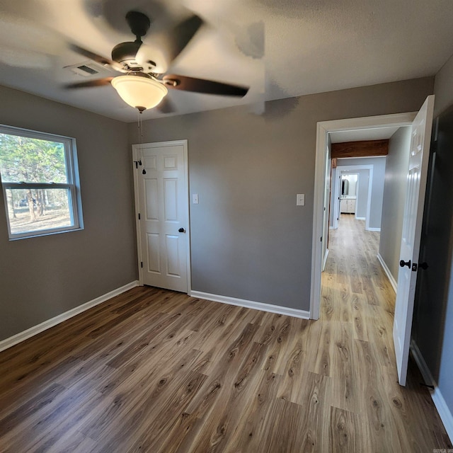 unfurnished bedroom with ceiling fan, baseboards, and wood finished floors