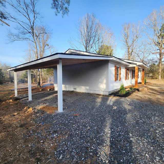 view of side of home with a carport, crawl space, and gravel driveway