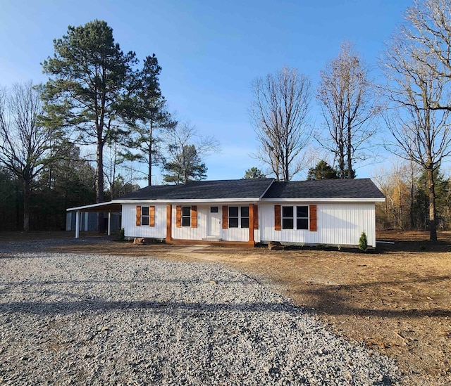 ranch-style home with a carport, gravel driveway, and covered porch