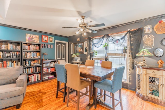 dining room with a ceiling fan, crown molding, and wood finished floors