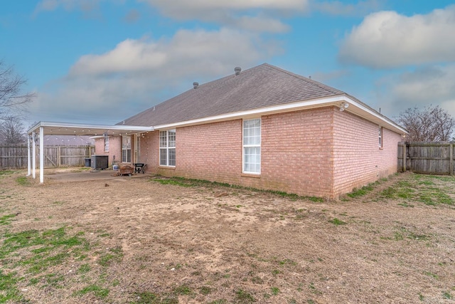 back of house with brick siding, fence, and central AC unit