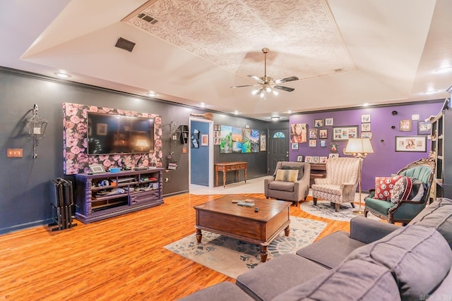 living room featuring ceiling fan, wood finished floors, a raised ceiling, and baseboards