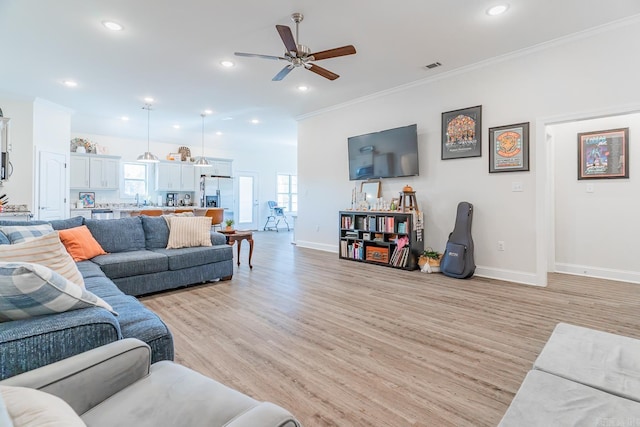 living area featuring light wood-style floors, recessed lighting, visible vents, and ornamental molding