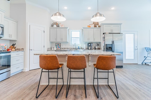 kitchen featuring light wood-type flooring, stainless steel appliances, and a kitchen breakfast bar