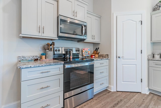 kitchen featuring appliances with stainless steel finishes, baseboards, light wood finished floors, and light stone countertops